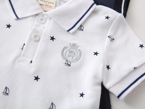 Detail of white cotton boys' polo shirt with blue star prints and crest embroidery