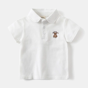 Detail of white cotton polo shirt featuring brown lucky bear embroidery and smooth buttons