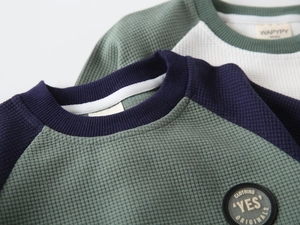 Detail of waffle knit fabric and raglan sleeve stitching on kids' sweatshirts
