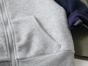 Detail view of cotton knit fabric texture with zipper and ribbed hem on boy's hoodie