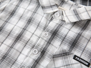 Close-up of boys black and white plaid shirt with FASHION label and white resin buttons