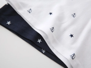 Detail of piqué cotton fabric showing nautical sailboat and star prints on polo shirts
