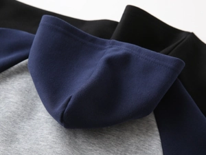 Detailed view of color-block stitching on the hood and raglan shoulder of the boys' hoodie
