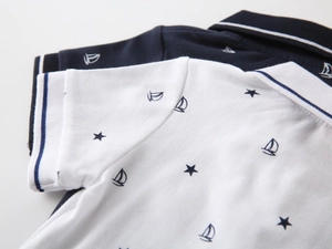 Detailed view of the piqué fabric with sailboat and star patterns on polo shirts