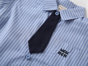 Dettaglio camicia a righe azzurre da bambino con cravatta blu e ricamo