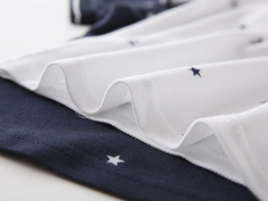 Macro shot of breathable navy cotton pique fabric with white star print on polo shirt