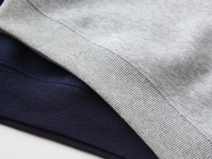 Close-up of elastic ribbed cuffs and stitching on heather gray and navy kids hoodies