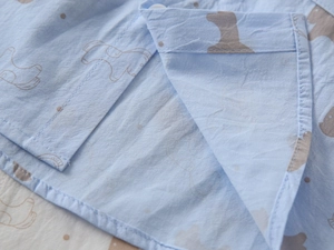 Close-up of double-stitched hem on boys' light blue shirt with animal print