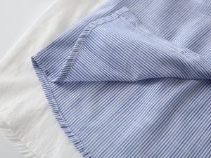 Detailaufnahme des blau-weiß gestreiften Baumwollhemdes mit feinen Nähten und Stoffstruktur