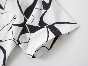 Vue détaillée des coutures et du motif à tourbillons noirs sur la chemise garçon à manches