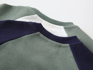 Detailed close-up showing textured waffle knit fabric and ribbed crewneck stitching