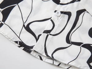 Détail du tissu en coton avec motifs floraux noirs et un bouton blanc sur la chemise