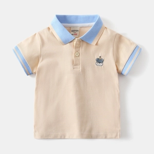 Detail of light orange boys' polo shirt featuring a blue collar and cartoon dog embroidery