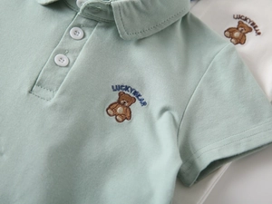 Close-up of light green boys polo shirt featuring lucky bear embroidery and classic collar