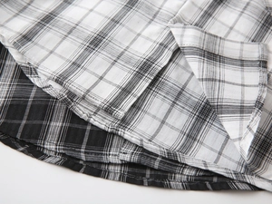 Detail of the double-stitched hem on a black and white checkered cotton boy shirt