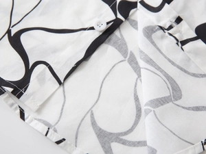 Détail de chemise blanche garçon avec motifs floraux noirs et texture en lin