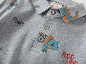 Detailed view of cartoon dinosaur print and three-button polo collar on toddler grey shirt