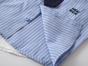 Dettaglio camicia a righe blu da bambino con colletto blu scuro e ricamo