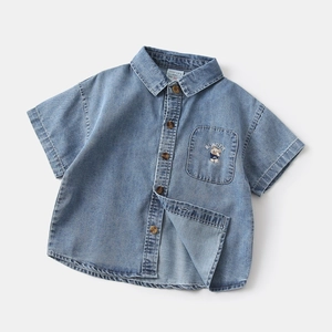 Close-up of kids denim shirt featuring teddy bear embroidery and brown buttons