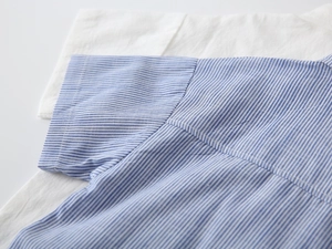 Detailaufnahme des blau-weiß gestreiften Baumwollhemdes mit präzisen Nähten am Ärmel