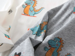 Close-up of soft cotton knit fabric featuring vibrant cartoon dinosaur prints for boys