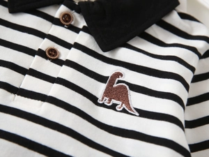 Close-up of kids striped polo shirt featuring brown dinosaur embroidery and wooden buttons