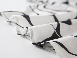 Vue détaillée du motif géométrique noir sur le tissu blanc d'une chemise d'été