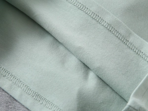 Macro view of mint green polo shirt showing detailed double-needle stitching and fabric