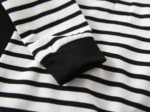 Detail view of the black and white striped knit fabric and elastic ribbed cuffs on the sleeve