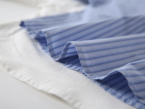 Macro della trama a righe bianche e blu e cuciture pulite sulla camicia da bambino
