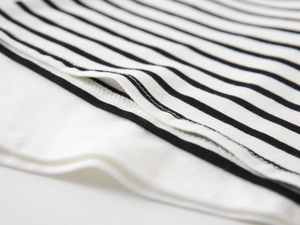 Detail shot of the double-needle stitching on the hem of a striped knit polo shirt