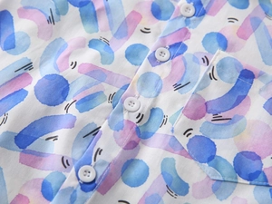Macro view of colorful watercolor patterns on kids shirt with white button and chest pocket