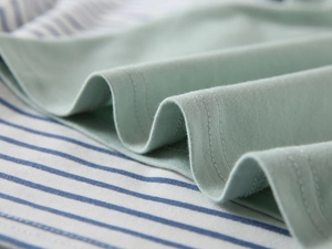 Detail shot of double-needle stitching on a light green cotton polo shirt for boys