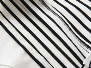 Close-up of high-quality flatlock stitching on a black and white striped cotton polo shirt