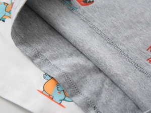 Detailed macro view showing high-density overlock stitching on cotton dinosaur print polo
