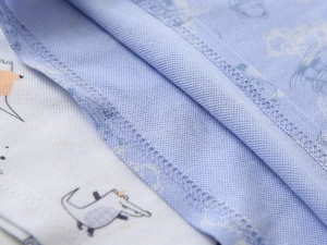 Detailed close-up of cartoon crocodile print and breathable mesh fabric on polo shirt