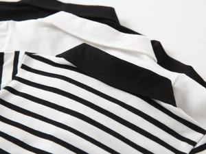 Detailed view of children's polo shirts in black, white, and striped knitted cotton fabric