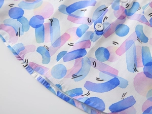 Close-up of boys' summer shirt showing colorful watercolor print and white resin buttons