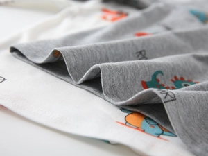 Detailed macro view of soft cotton knit fabric with colorful cartoon dinosaur prints