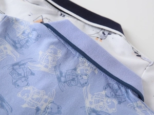 Detail of baby boy's blue polo shirt featuring pique knit fabric and cartoon bear print