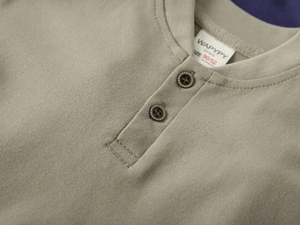 Détail du tissu en coton piqué vert olive avec boutons en bois sur polo pour enfant