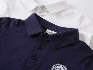 Close-up of boys cotton polo shirt showing navy knit texture and collar embroidery detail