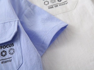 Detail of light blue and white boy's shirts showing the pocket print and crinkle fabric