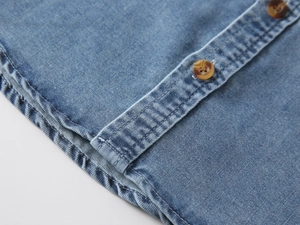 Detailed view of washed denim shirt featuring textured fabric and amber buttons