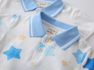 Close-up of boys white polo shirt featuring blue star prints and ribbed collar details