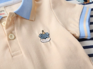 Detail of embroidered cartoon bear on cotton polo shirt with blue striped collar