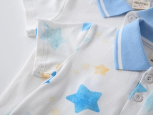 Detail of boys white cotton polo shirt featuring blue and yellow watercolor stars