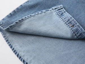 Detailed macro view of denim shirt curved hem with premium double-needle stitching