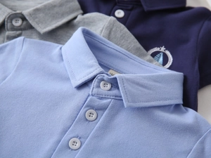 Dettaglio macro di polo in cotone piqué con colletto a bottoni e stemma ricamato