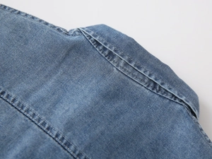 Macro shot of blue denim shirt showing twill texture and durable double stitching